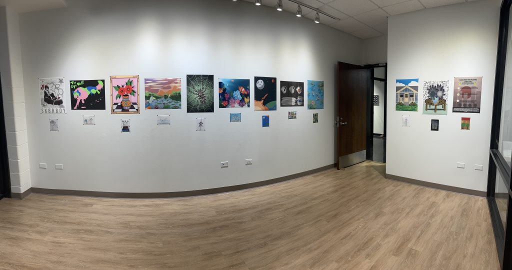 panorama of the inside of the exhibition room with several posters lined up on the wall with smaller photos underneath them