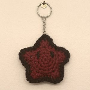 crochet burgundy star keychain with a black border and eyes